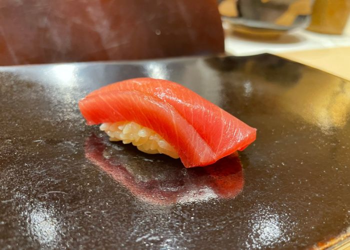 Fresh salmon nigiri is being served on a dark grey serving board at Sushi Rakumi, a Michelin star sushi restaurant in Kyoto.